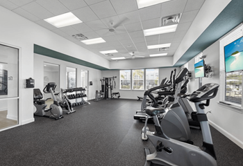 A gym with a variety of exercise equipment including treadmills, stationary bikes, and weight machines.